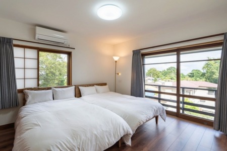 大きい窓から光差し込む寝室